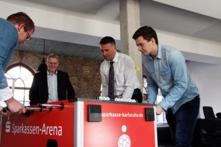 Drei Männer von der Firma CyberLab und Sparkassendirektor Marc Sesemann spielen am Tischkicker.